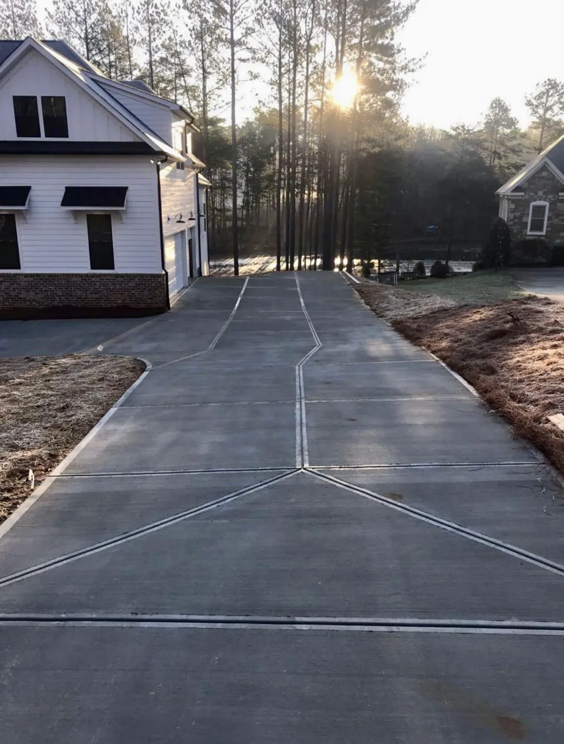 Long concrete driveway leading to a home at sunset
